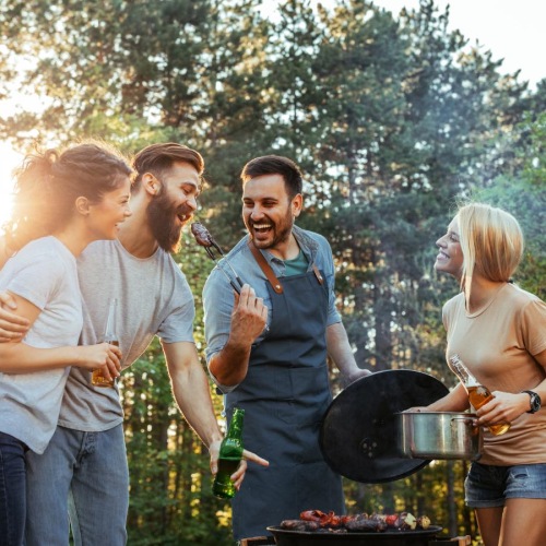 Enjoy lush greenspaces, modern comforts, and a true sense of community. a group of people standing outside around a grill
