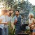 a group of people standing outside around a grill