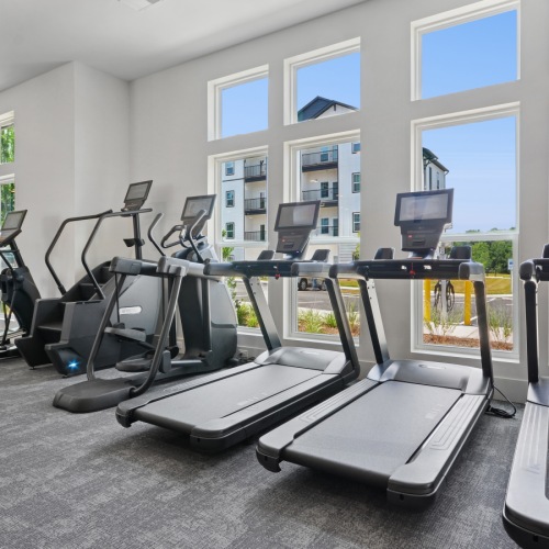 HIIT - CrossFit Fitness Room  A gym with treadmills, exercise bikes, and other equipment.